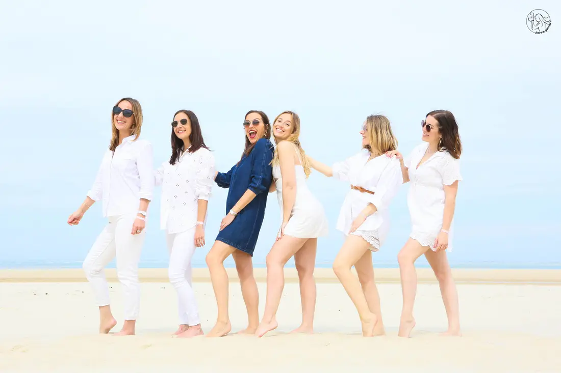 Groupe de six amies souriantes, habillées de blanc, sur une plage du Bassin.