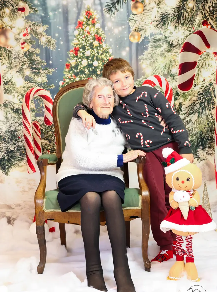 Une grand-mère et son petit-fils enlacés dans un décor de Noël enneigé.